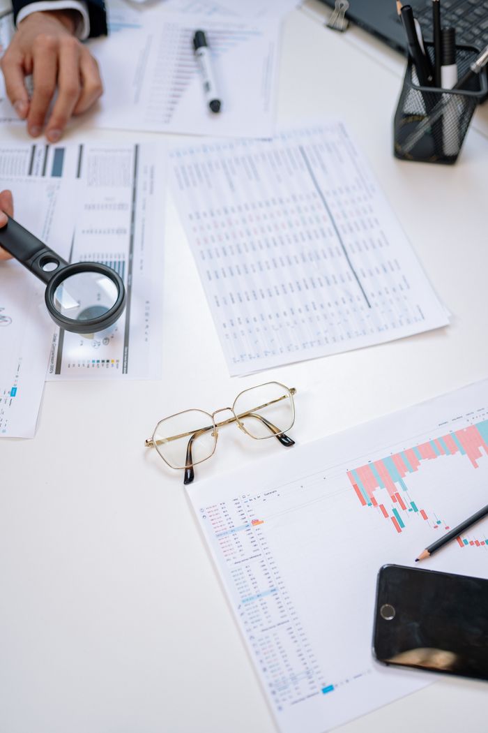 O nas Flat lay of business documents with magnifying glass, glasses, and smartphone on a desk.